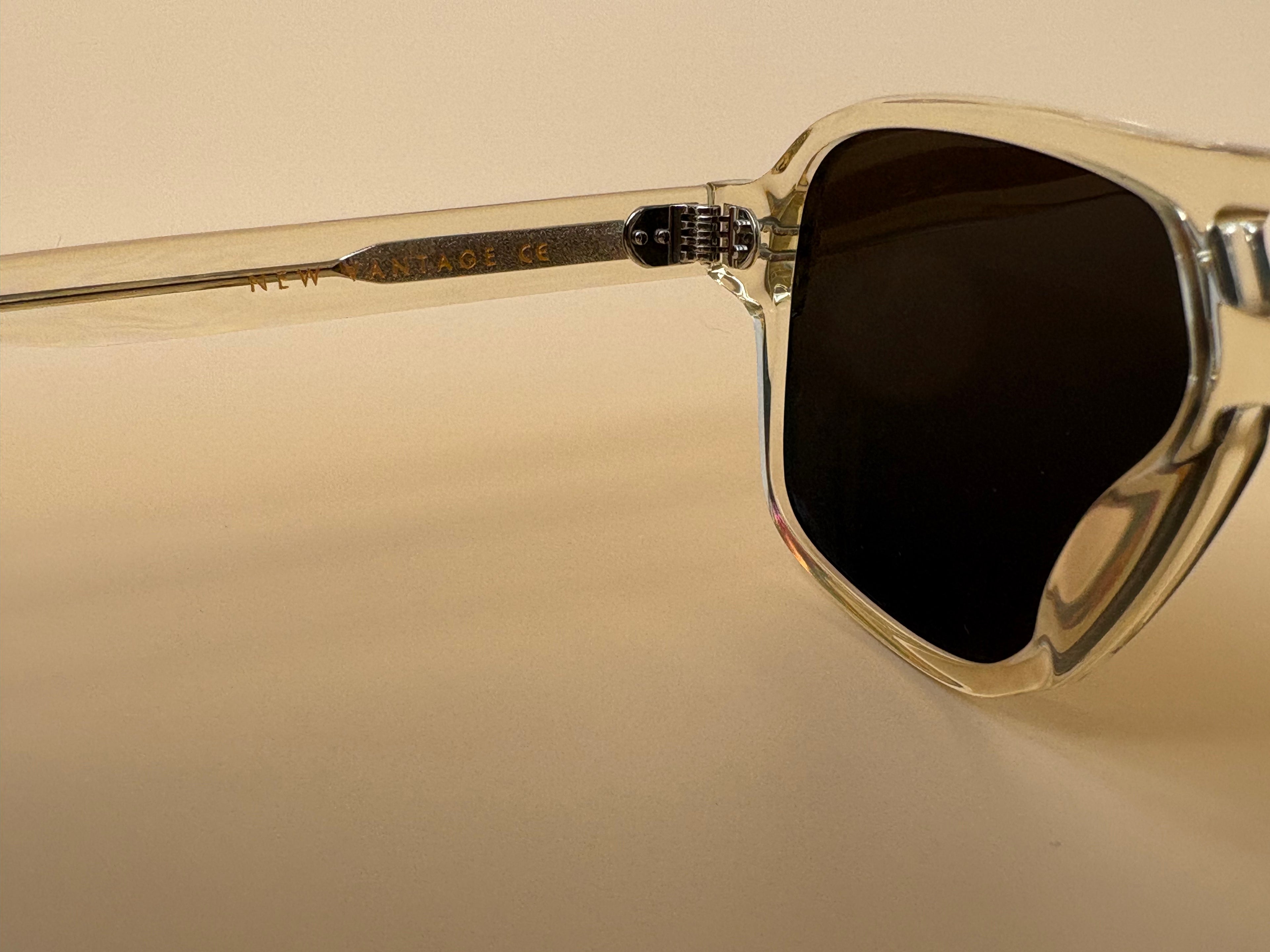 Gold-framed sunglasses with dark lenses on a beige background